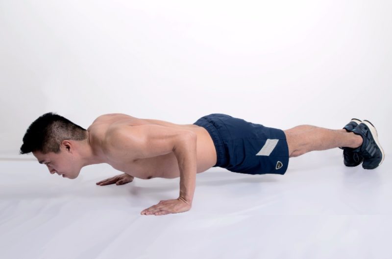 man doing four limbed staff pose yoga